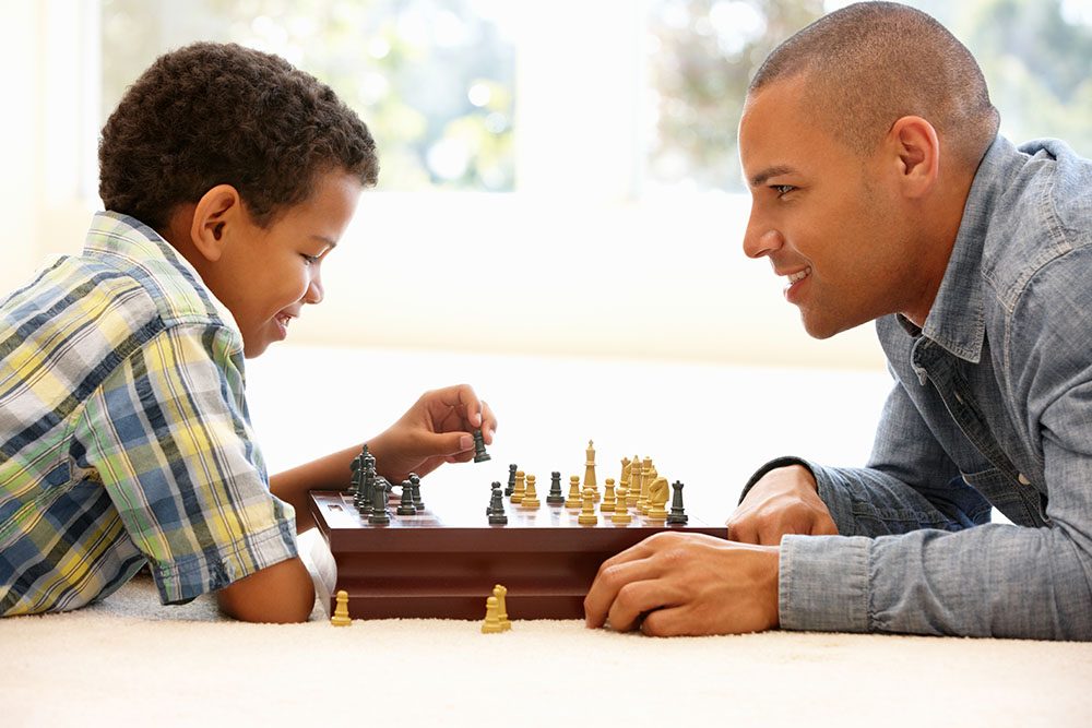 Father and son playing chess on a clean carpet